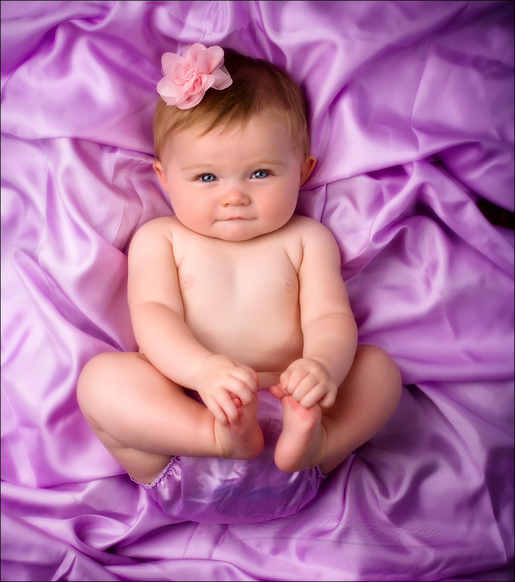 cute baby girl looking up at viewer in satin diaper cover on satin cloth