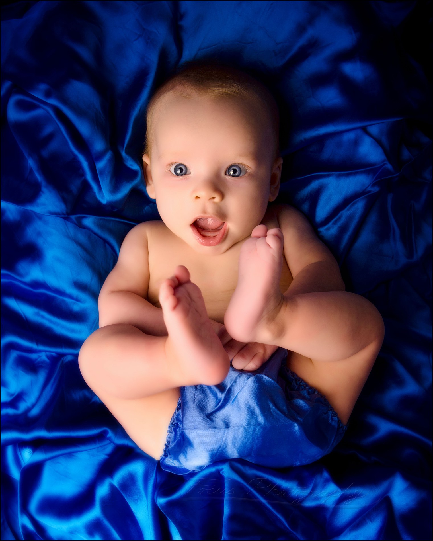 baby boy in blue diaper cover looks up at camera