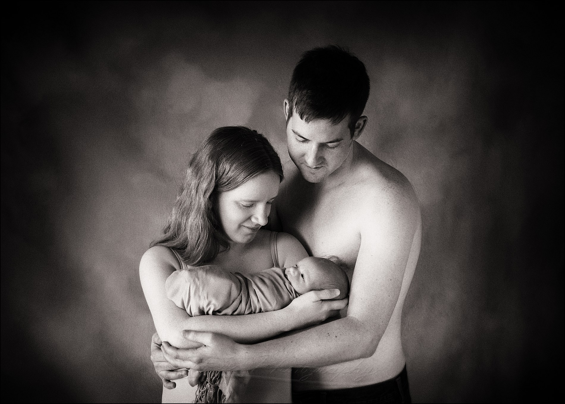 family photo of parents and newborn baby in photography studio