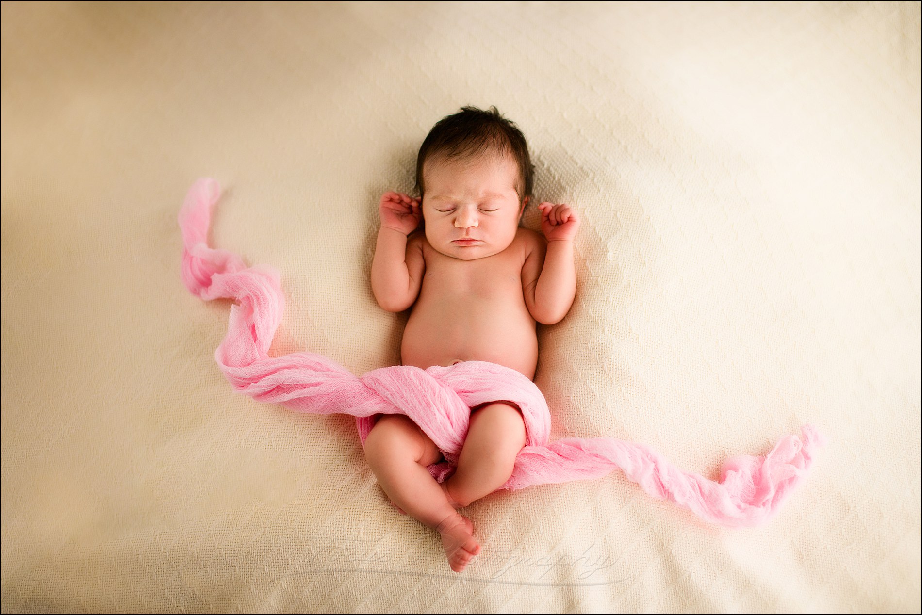 newborn baby girl and pink swaddling cloth on cream blanket