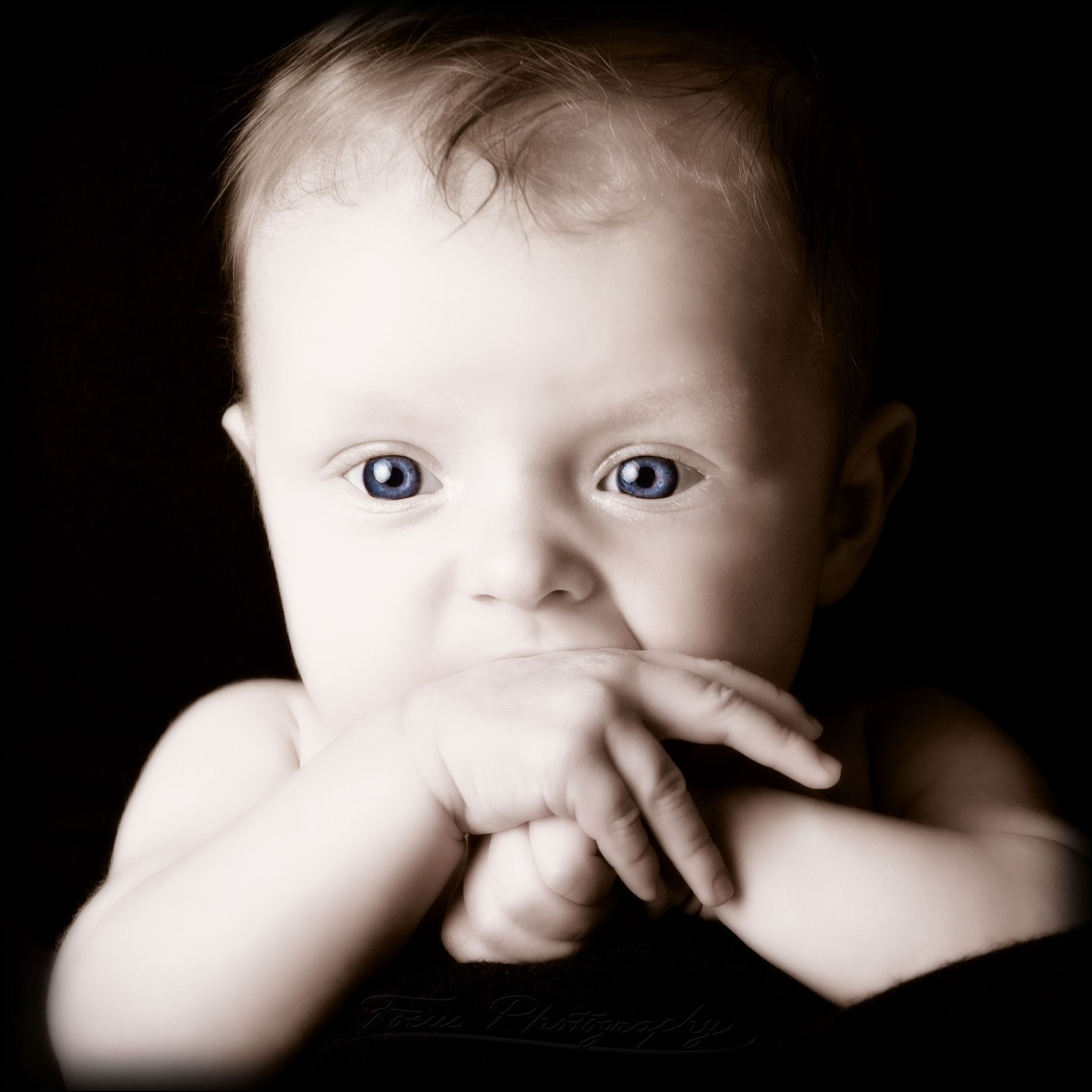 blue eyes look out from baby in black and white image
