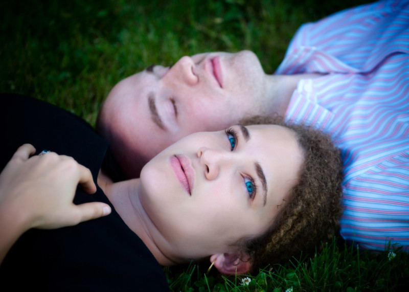 engaged couple laying on grass with serene expressions