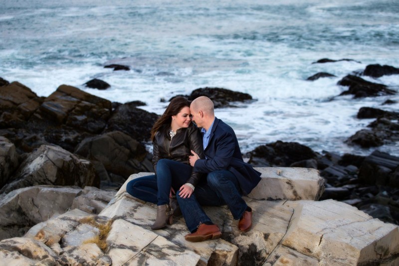 engaged couple on rocks by ocean
