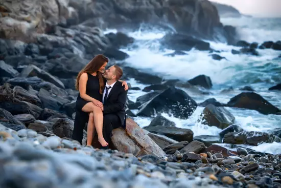 Engagement couple on the rocks with stormy waves at Fort Williams in Cape Elizabeth, ME