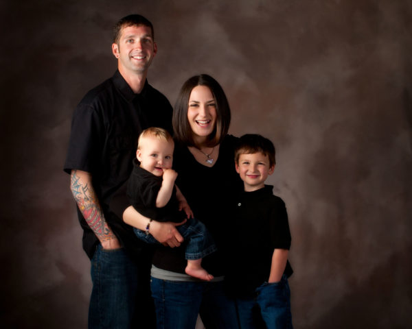 family wearing black and denim photographed in studio on brown background