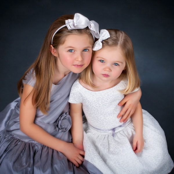 little girls looking up at camera in kids' picture at family portrait studio