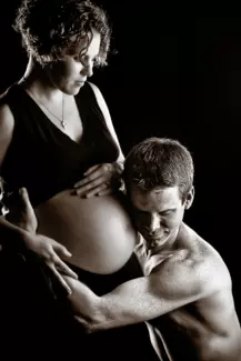 couple with pregnant belly in black and white portrait in maine photography studio.