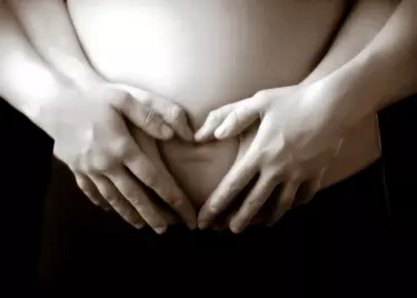hands on belly in shape of heart during pregnant belly photo shoot