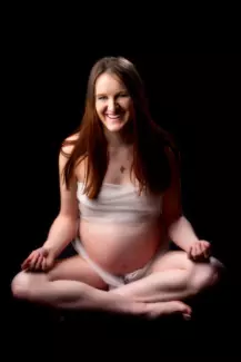 pregnant belly photo of expecting mother sitting cross-legged in maine portrait photography studio