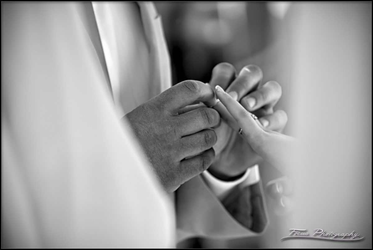 the groom slides the wedding band on the bride's finger