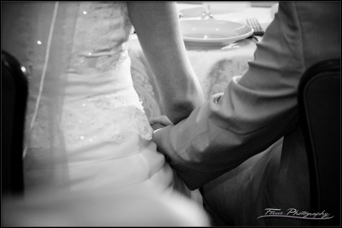 bride and groom hold hands under the table