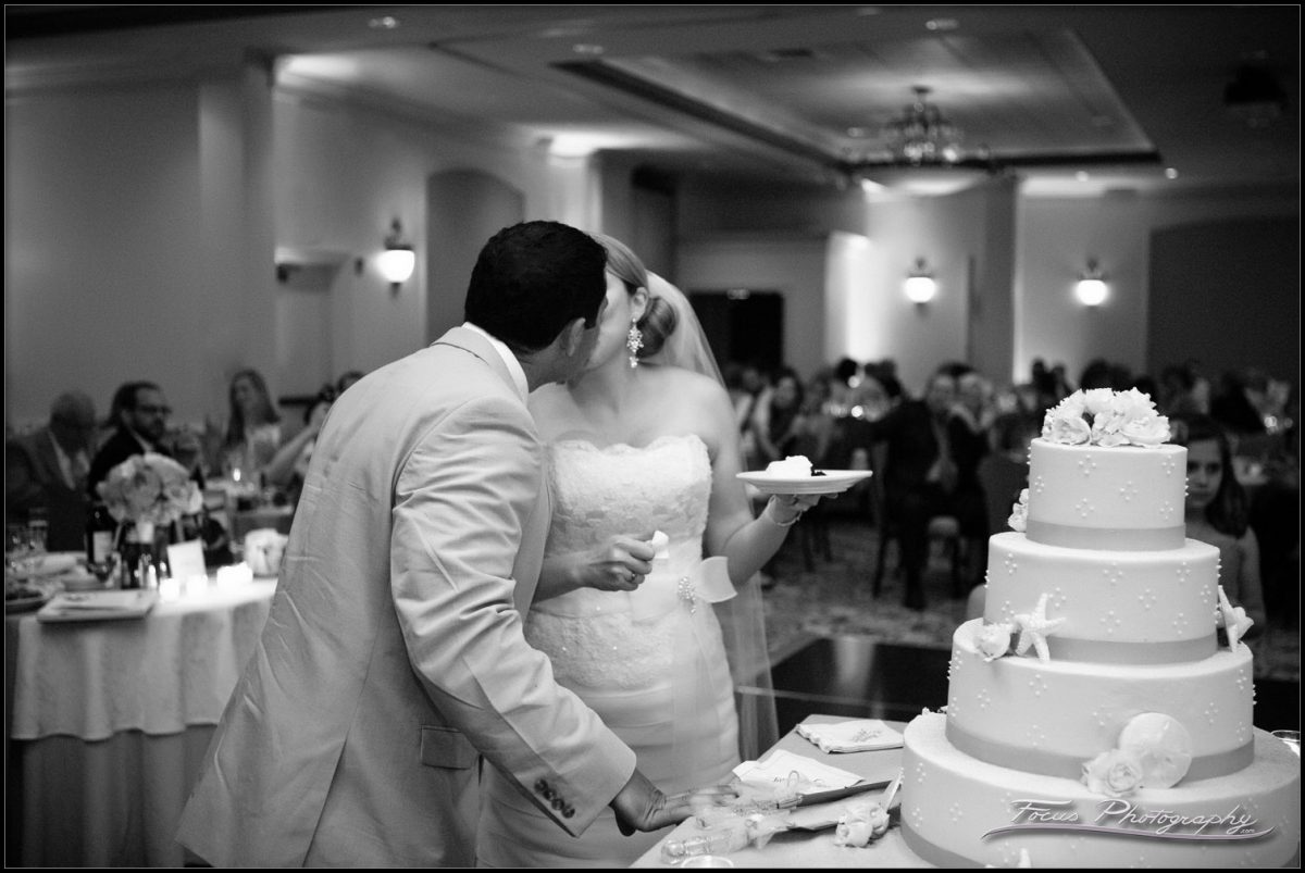 the bride and groom kiss at the wedding cake
