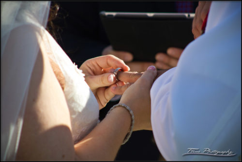 Bride places the grooms ring on his finger during