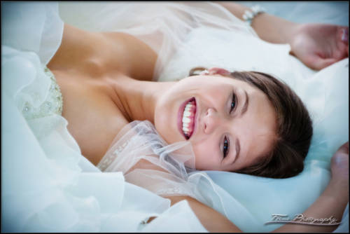 a happy portrait of a bride laying on the ground