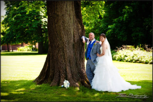 the bride and groom leaning against a tree