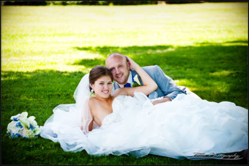 The groom and bride recline on the lawn