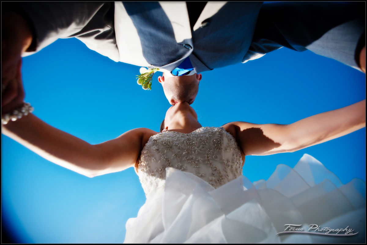 bride and groom kiss under the blue sky