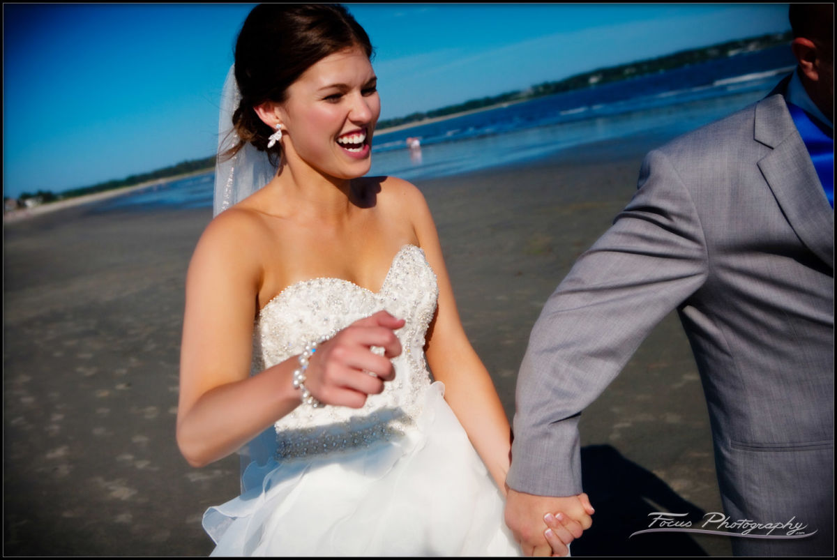 the bride and groom run across the beach