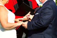 Ring exchange - groom puts wedding band on bride's finger.