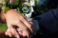 Hands and wedding rings by flowers.