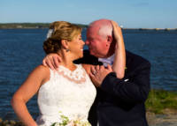 Bride and groom kiss with casco bay in background.