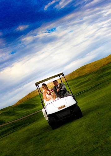 Bride and groom riding a golf cart on green hills, ideal for Red Barn Weddings in South Berwick Maine at Outlook Farm. Perfect for wedding photography. 