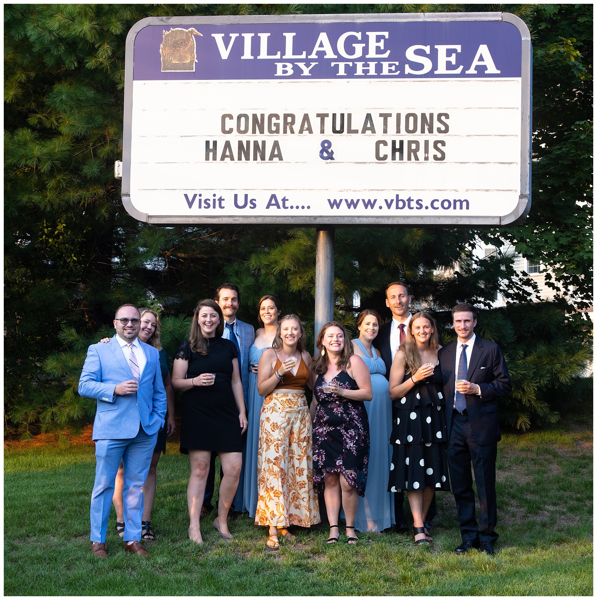 family poses in front of sign at village by the sea