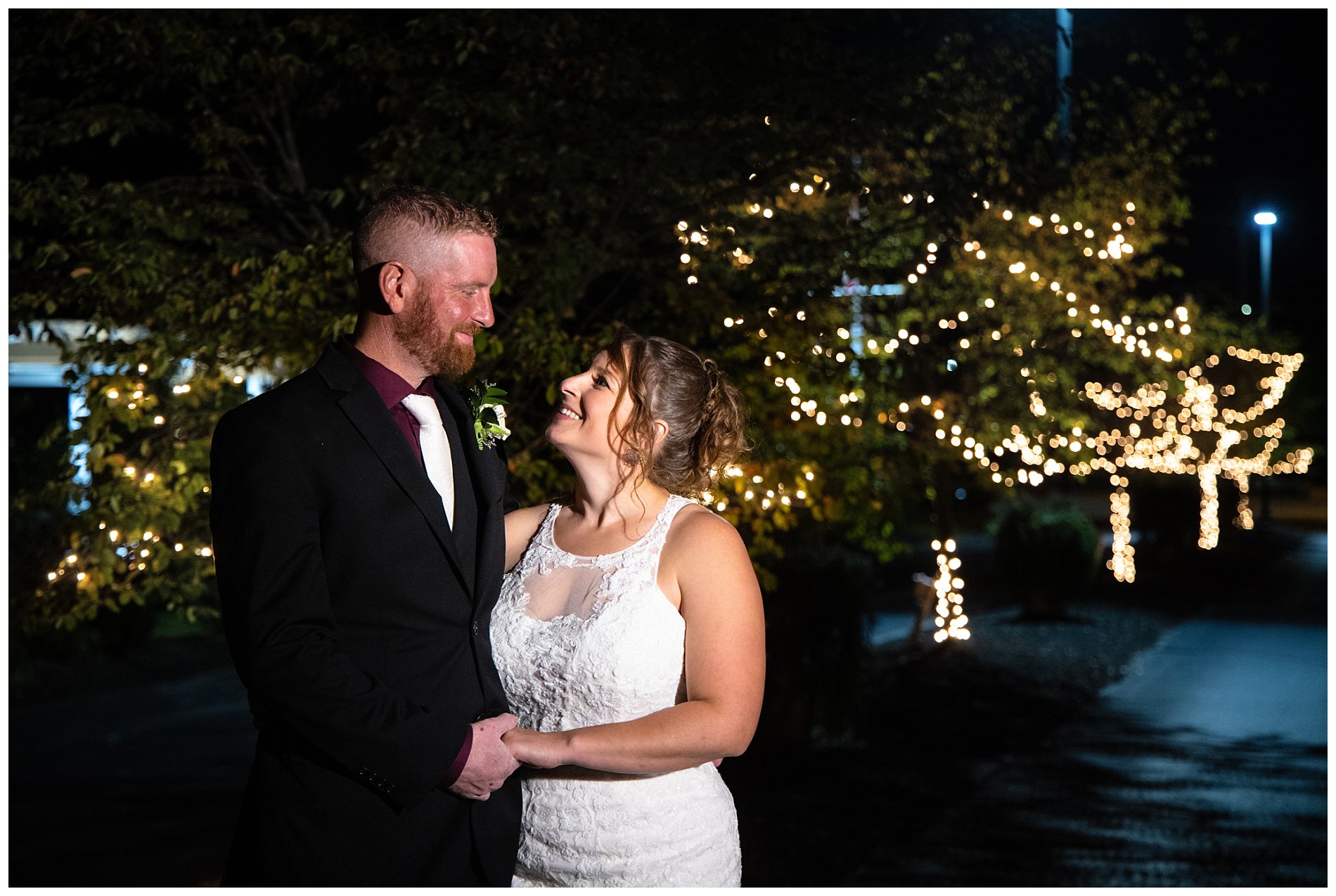 bride and groom outdoors at night with christmas lights in tree branches