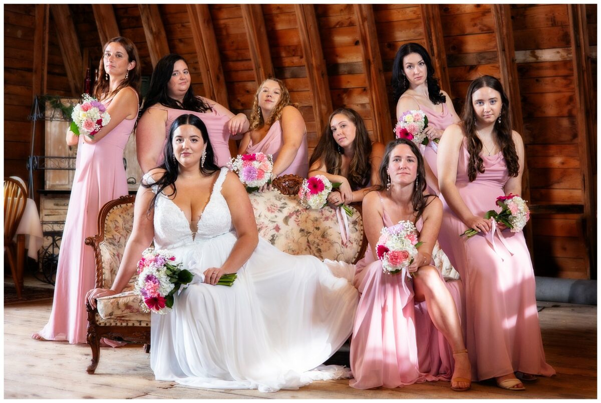 wedding portrait of bride and party on upholstered couch in barn