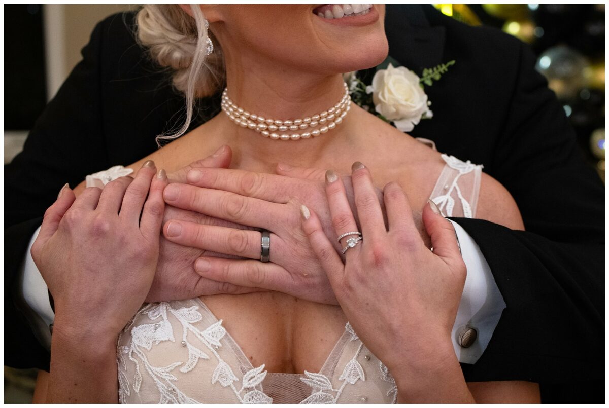 wedding rings on hands as couple embraces