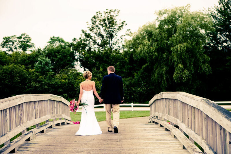 Bride and groom on wooden bridge at Samoset Resort Bride and groom walk hand in hand on a wooden bridge at Samoset Resort Rockport Maine captured by Samoset Photographer for Midcoast Weddings.