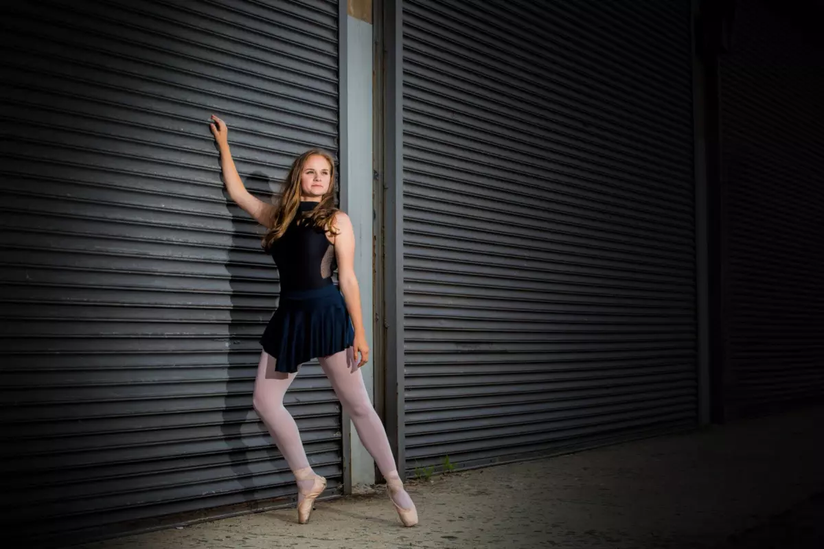 ballet dancer leans on urban steel doors in downtown portland for senior portrait