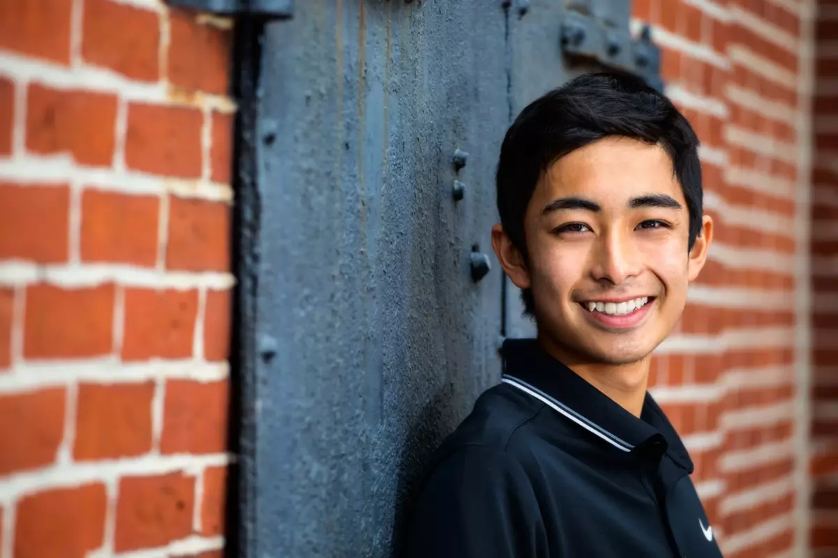 downtown portland photo shoot of maine high school senior boy on brick wall with black door