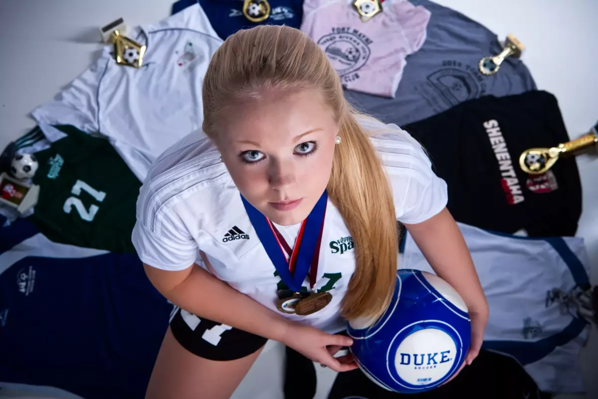 female athlete photographed with sports jerseys and volley ball for unique senior pictures in maine