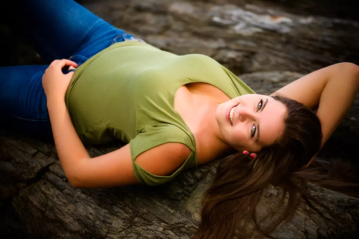 girl in green shirt lays on beach in maine for senior pictures
