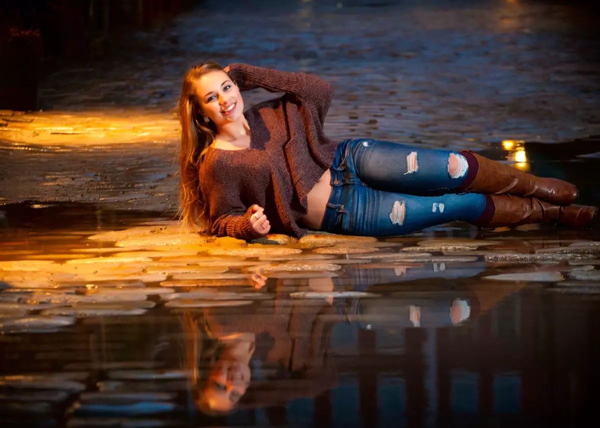 girl in torn jeans photographed laying on cobblestone streets in portland maine for senior pictures