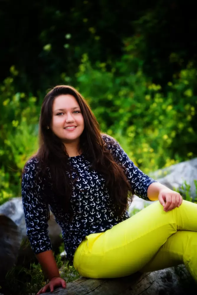 girl in yellow pants with yellow flowers at beach in maine for senior photos
