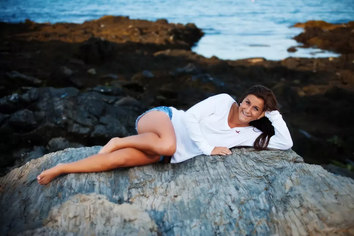 girl on rock for senior pictures at the beach in maine