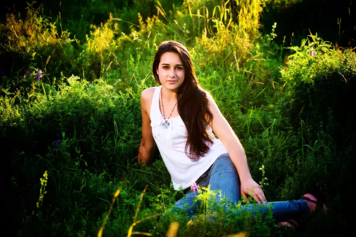 girl seated in grass during senior photos at maine audubon center's gilsland farm in falmouth maine