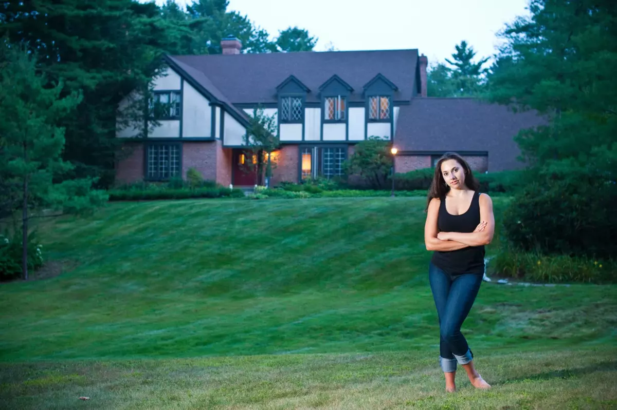 girl stands in front of her house for senior picture in maine