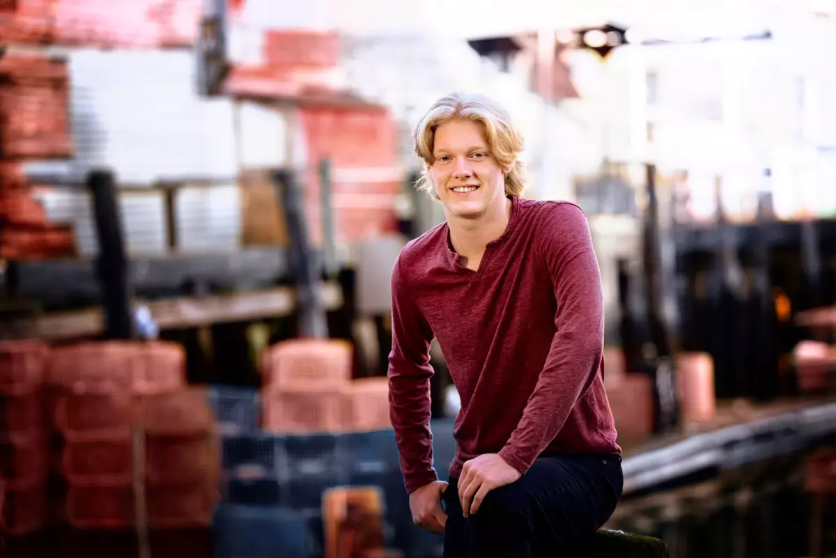 greely high school boy in red shirt photographed at portland, maine's waterfront with lobster traps and fishing boats for senior pictures