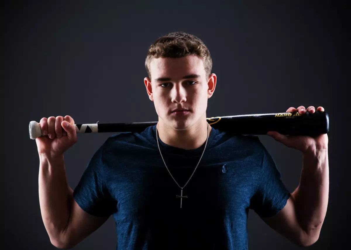 high school athlete holds bat for sports poster in senior pictures maine