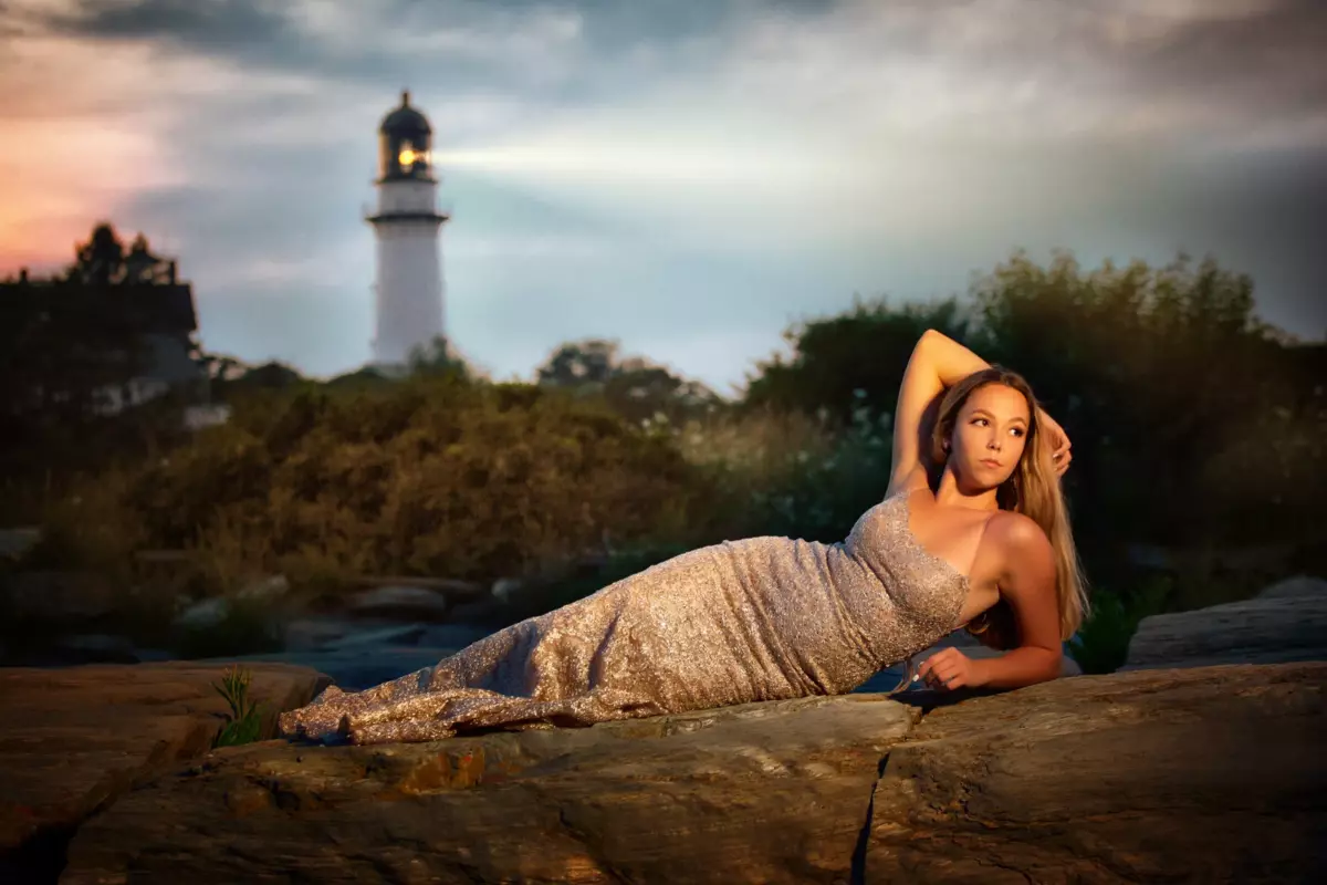 high school girl in sequined prom dress at beach in cape elizabeth maine for senior portraits with lighthouse