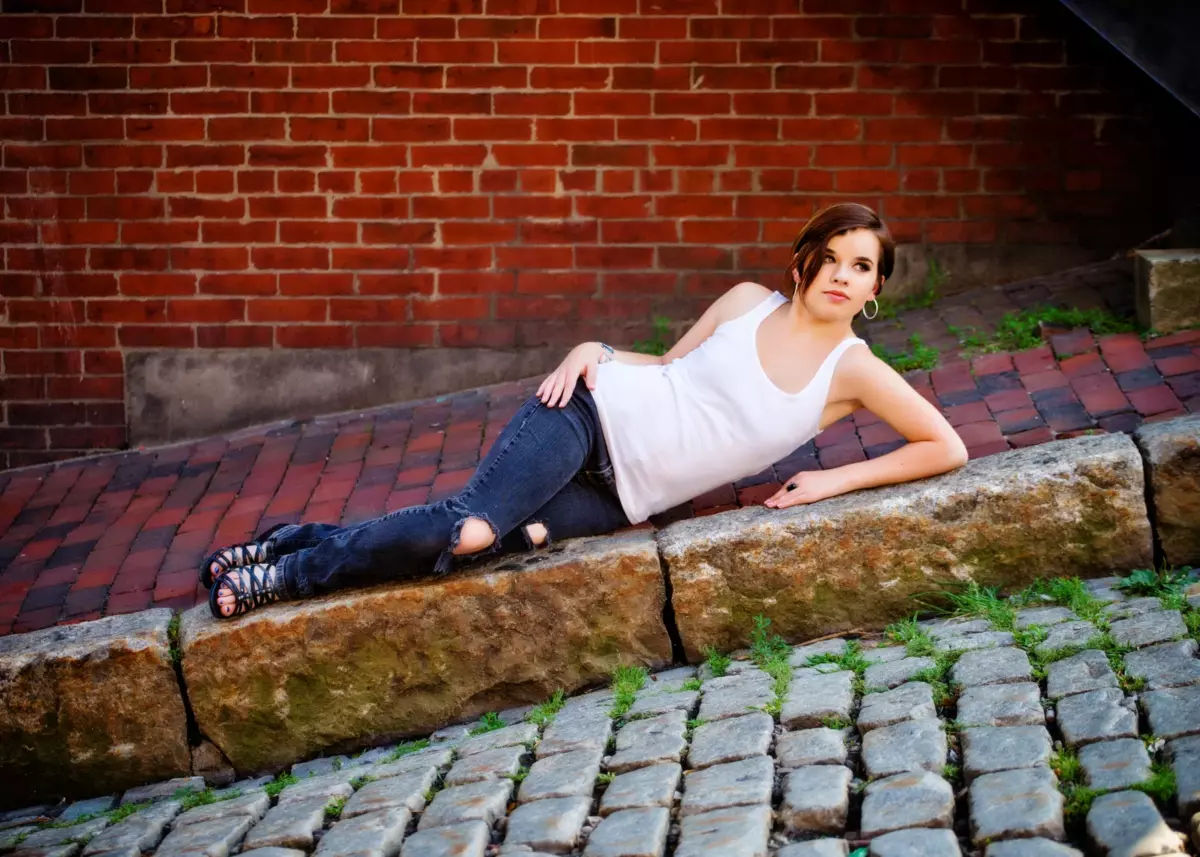 high school girl lays on sidewalk for senior pictures in portland maine