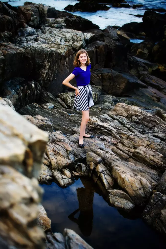 high school girl on rocks at beach in maine for cool senior pictures
