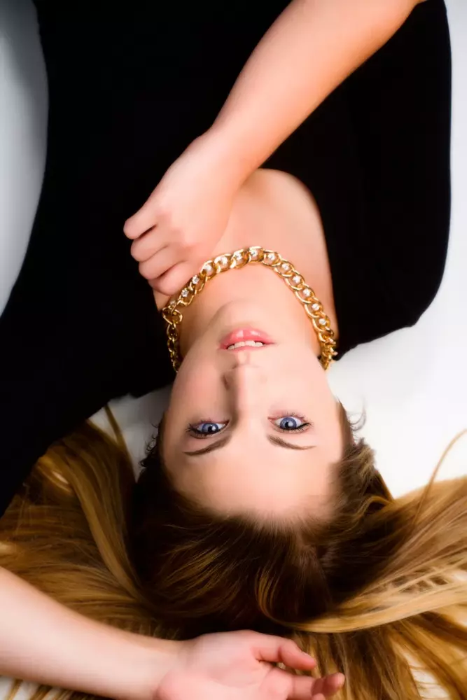 high school girl photographed in studio laying on floor upside down