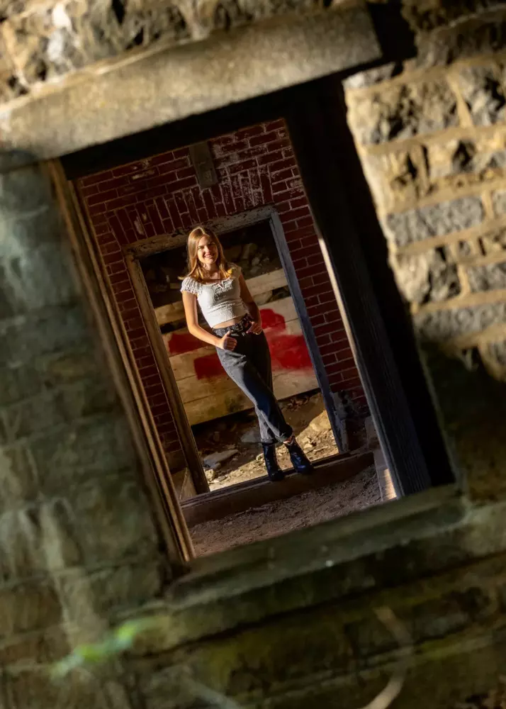 high school girl photographed through windows at military fort in maine for senior pictures