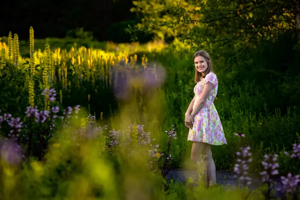 high school senior girl photographed for graduation portraits in field of wild flowers in cape elizabeth, maine