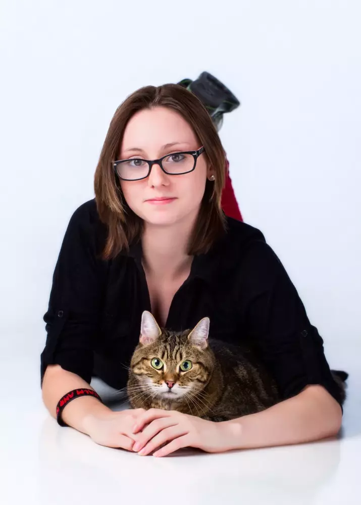 high school senior photographed on white floor and background with pet cat