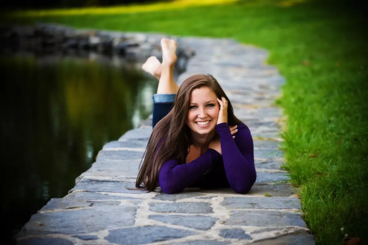 Maine high school senior girl lies on tiles beside reflecting pool at fort williams park in cape elizabeth